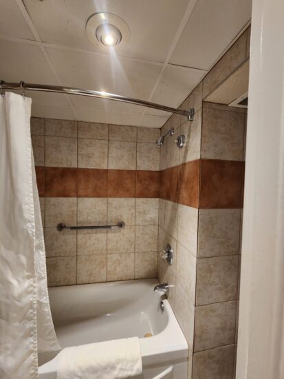 Salle de bain moderne avec douche à effet pluie à l’Hôtel La Saguenéenne, offrant confort et élégance.