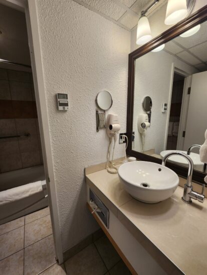 Salle de bain moderne avec douche à effet pluie à l’Hôtel La Saguenéenne, offrant confort et élégance.