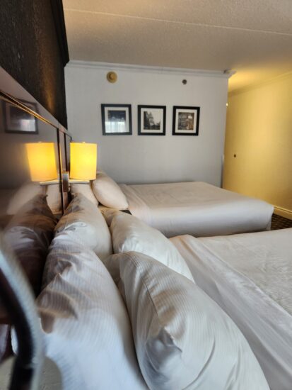 Cozy hotel room with two Queen beds, warm lighting, and a modern workspace – perfect for relaxation and productivity.