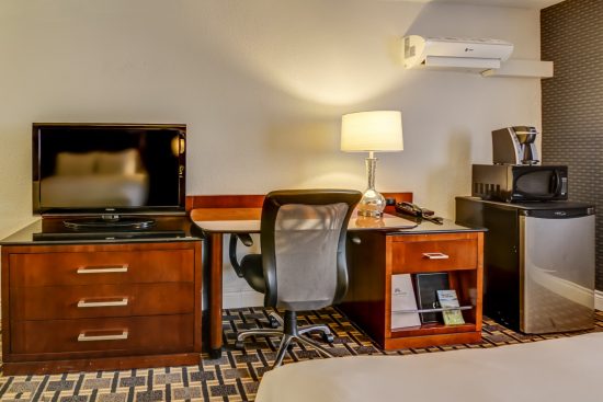 Modern hotel room with two Queen beds, a desk, mini-fridge, and microwave – perfect for a comfortable stay.