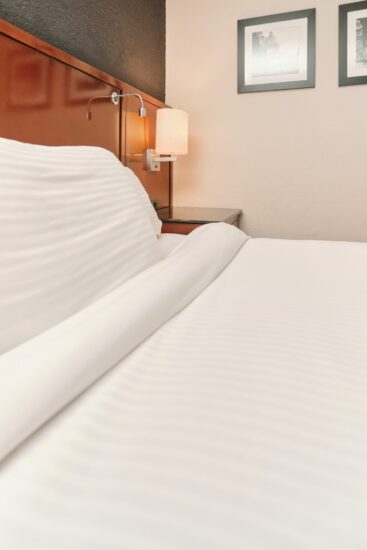 Photo d'une chambre 1 lit à l’Hôtel La Saguenéenne, avec deux grands lits, un coin salon, et un espace moderne et lumineux.