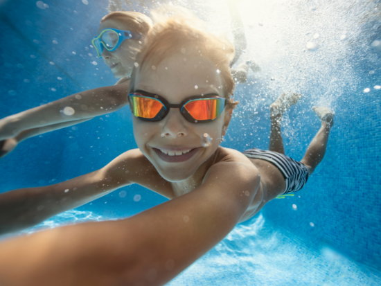 Des enfants nagent et s'amusent dans la piscine tropicale de l'hôtel La Saguenéenne à Saguenay, parfait pour des vacances en famille.
