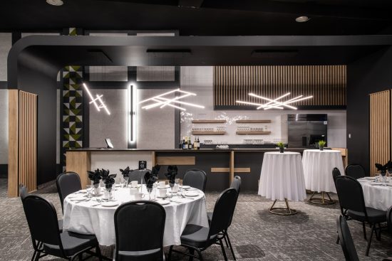 Grande salle de réception Rivière Chicoutimi A, équipée pour accueillir jusqu'à 525 personnes en configuration théâtre, avec éclairage moderne et décoration élégante - Hôtel La Saguenéenne