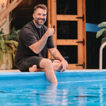 Un homme se détend après ses réunions d'affaires dans la piscine de l'hôtel La Saguenéenne, profitant d'un moment de relaxation.