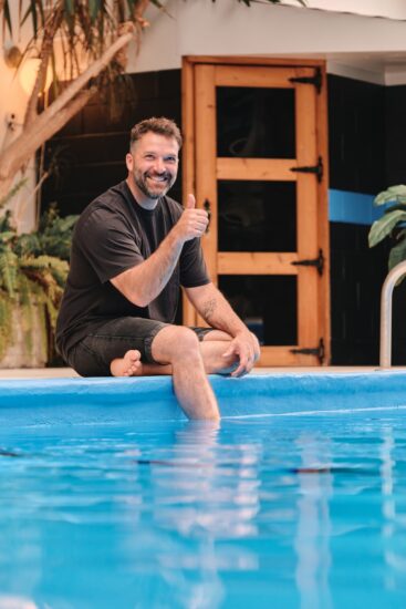 Un homme se détend après ses réunions d'affaires dans la piscine de l'hôtel La Saguenéenne, profitant d'un moment de relaxation.