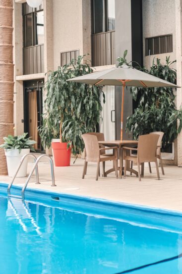 Piscine de l’Hôtel La Saguenéenne, entourée de verdure et offrant une ambiance chaleureuse pour une détente totale.