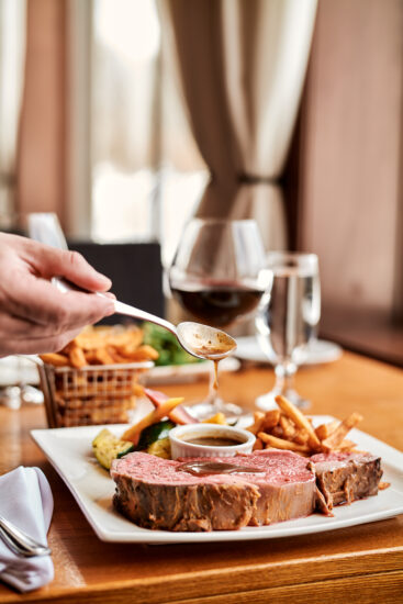 Côte de bœuf au jus juteuse, servie avec un verre de vin et des accompagnements savoureux.