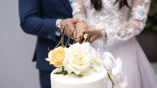 Gâteau de mariage orné de roses blanches dans une salle élégante de La Saguenéenne