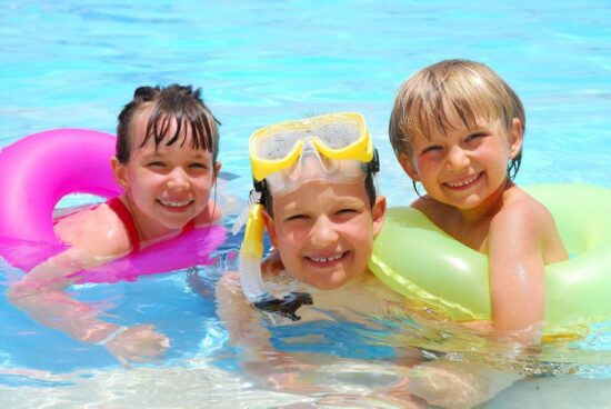 Smiling children playing in the pool at Hôtel La Saguenéenne – a family-friendly aquatic experience.