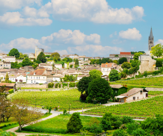 Ferme traditionnelle bretonne avec ses murs en pierre, entourée de champs verdoyants et sous un ciel bleu parsemé de nuages